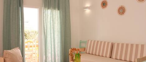 A living room with a sofa, a wooden table, and a window with curtains.
