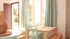 Una habitación con una mesa de madera, dos sillas, un banco y una cesta de mimbre.