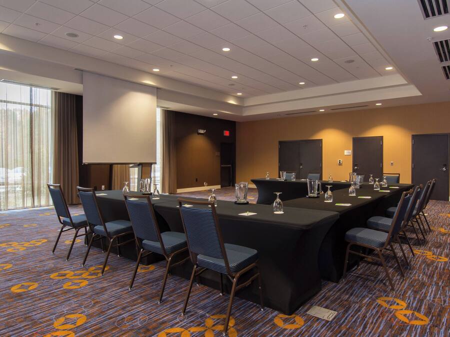Un salón de conferencias con una larga mesa, sillas y una pantalla para proyector.