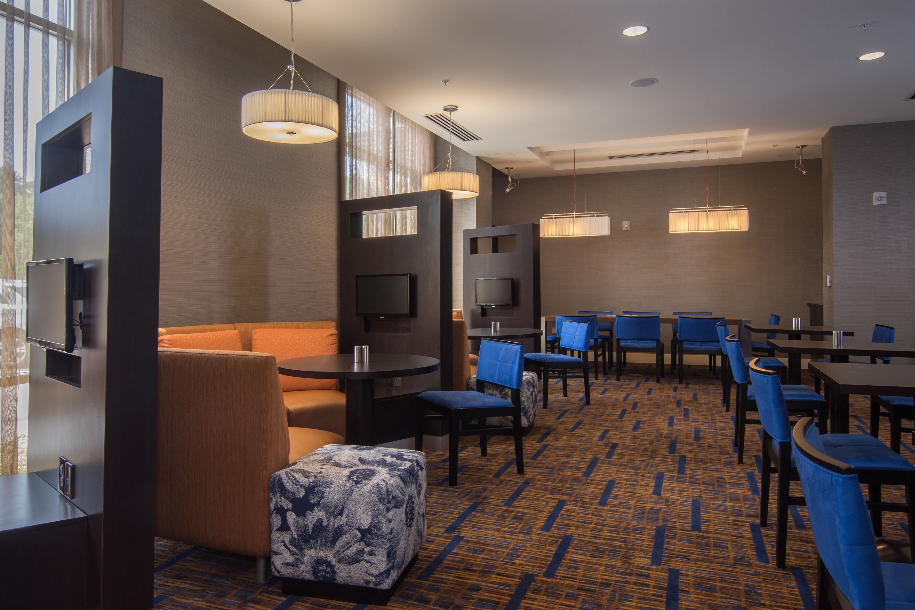 A hotel lobby with seating arrangements, tables, and a patterned carpet.