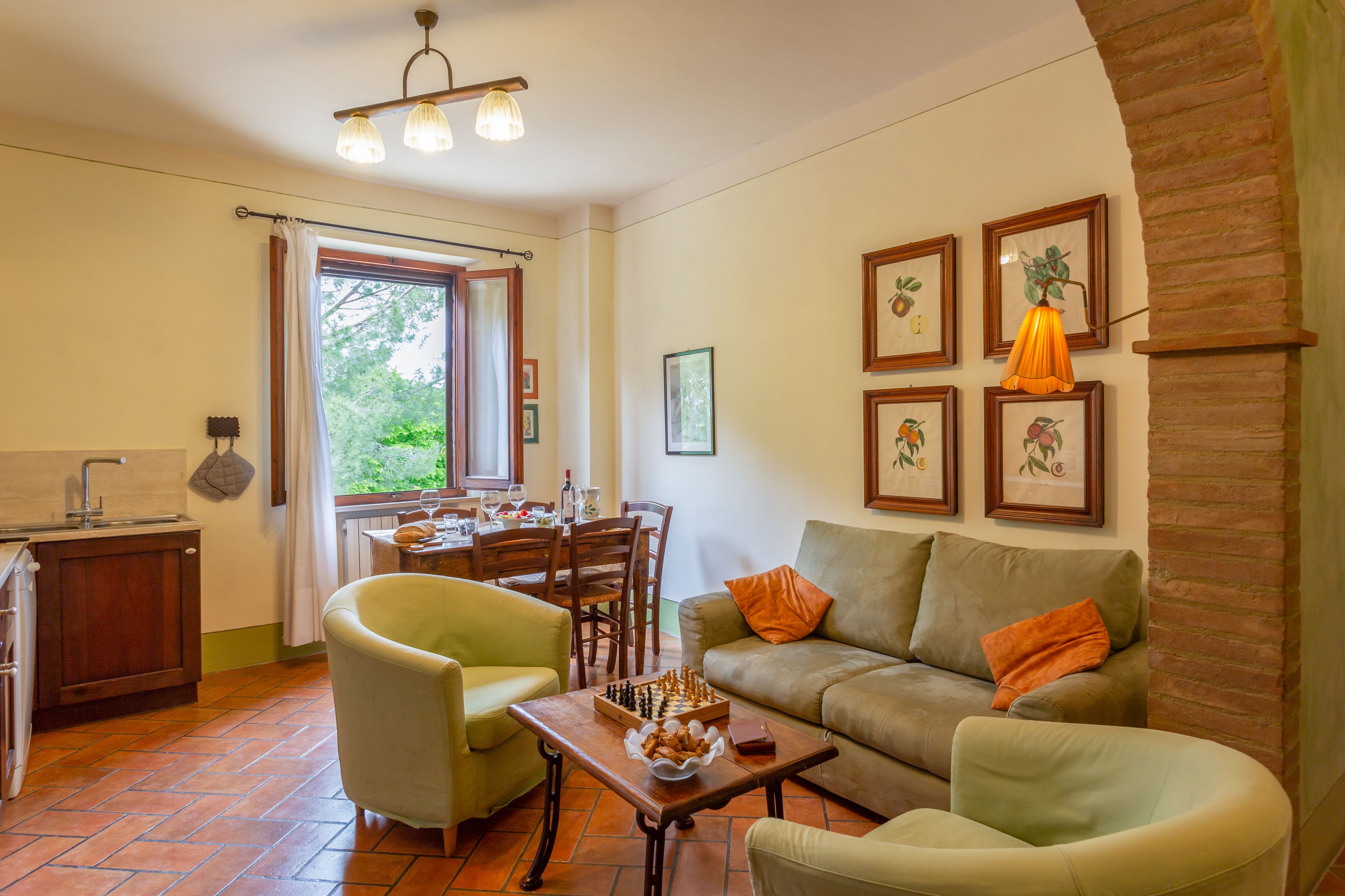 Un salon confortable avec un canapé, des fauteuils, une table à manger avec des chaises et un coin cuisine avec une fenêtre.