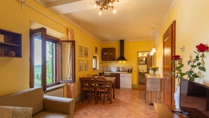 A cozy living room with a sofa, a dining table with chairs, and a kitchen area with a stove and cabinets. - Il Palazzetto (Siena)