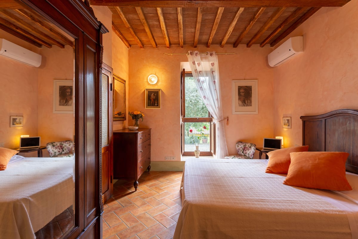 Une chambre avec deux lits, des têtes de lit en bois, une grande fenêtre donnant sur un beau paysage et un plafond en bois.