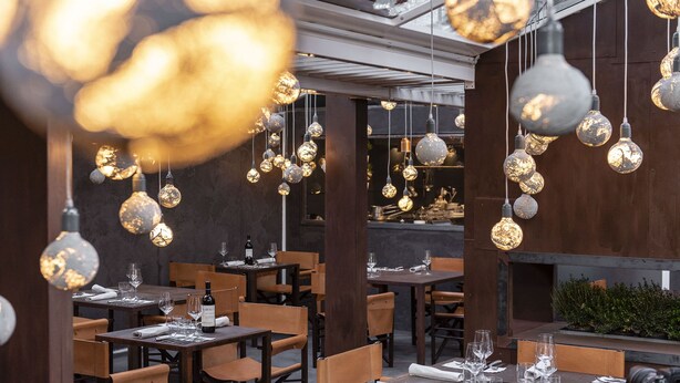 A restaurant interior with multiple dining tables, chairs, and hanging spherical light fixtures. - Hotel Astro Mediceo (Florence)