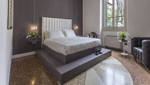 A modern bedroom with a large bed, a small seating area, and a view of the outdoors. - Hotel Astro Mediceo (Florence)