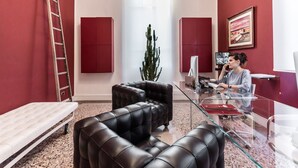 A modern living room with a glass coffee table, leather sofas, a cactus plant, and a ladder against the wall. - Hotel Astro Mediceo (Florence)