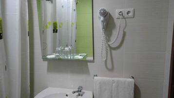 Un baño con lavamanos, espejo, secador de pelo y toallero.