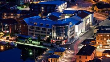 A modern hotel with a curved facade, multiple floors, and a waterfront view.