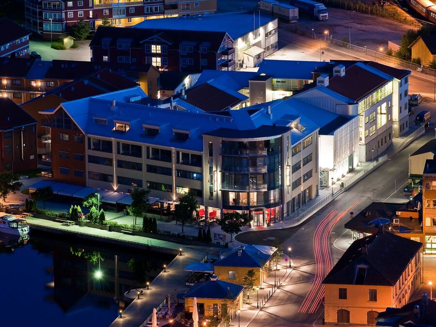 A modern hotel with a curved facade, multiple floors, and a waterfront view.