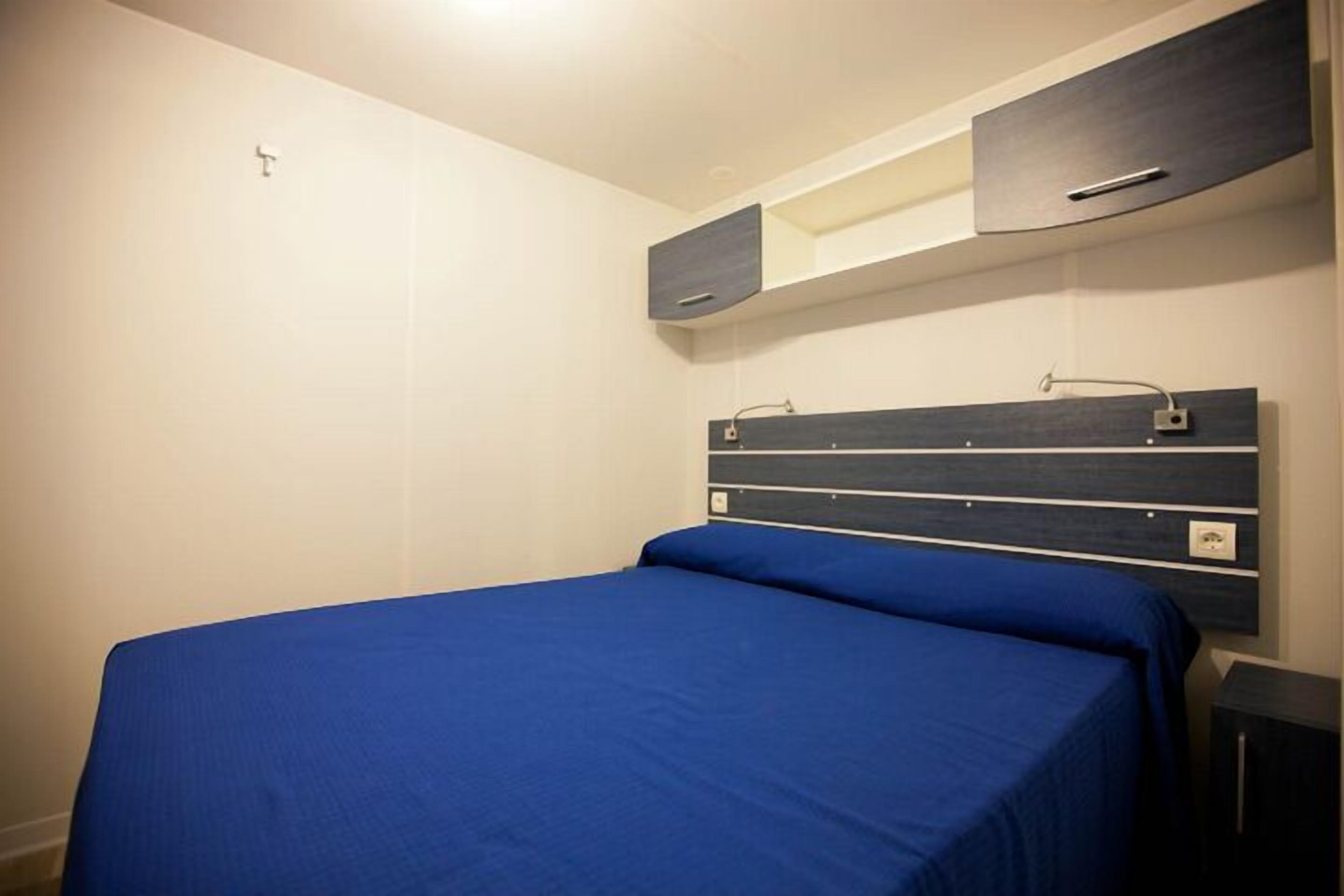Un dormitorio con cama, mesita de noche y armarios empotrados.
