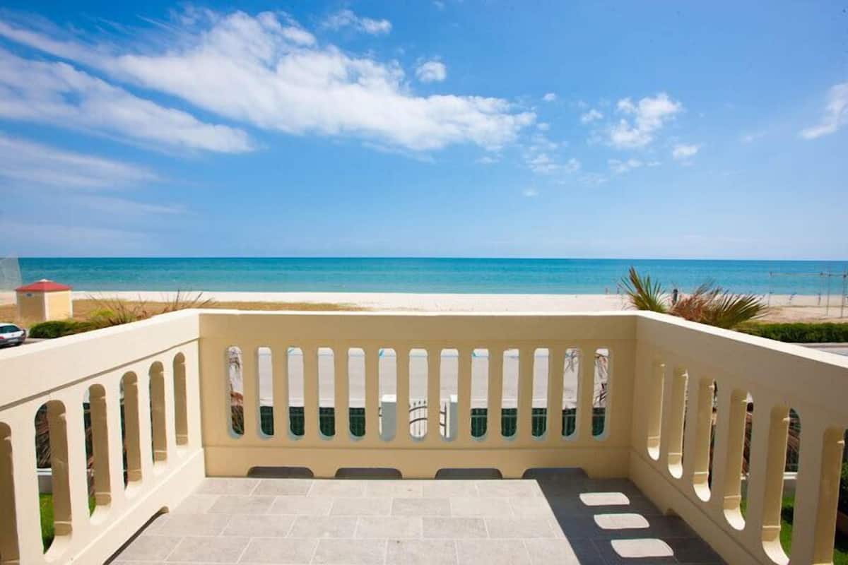 A balcony with a view of the beach and ocean.