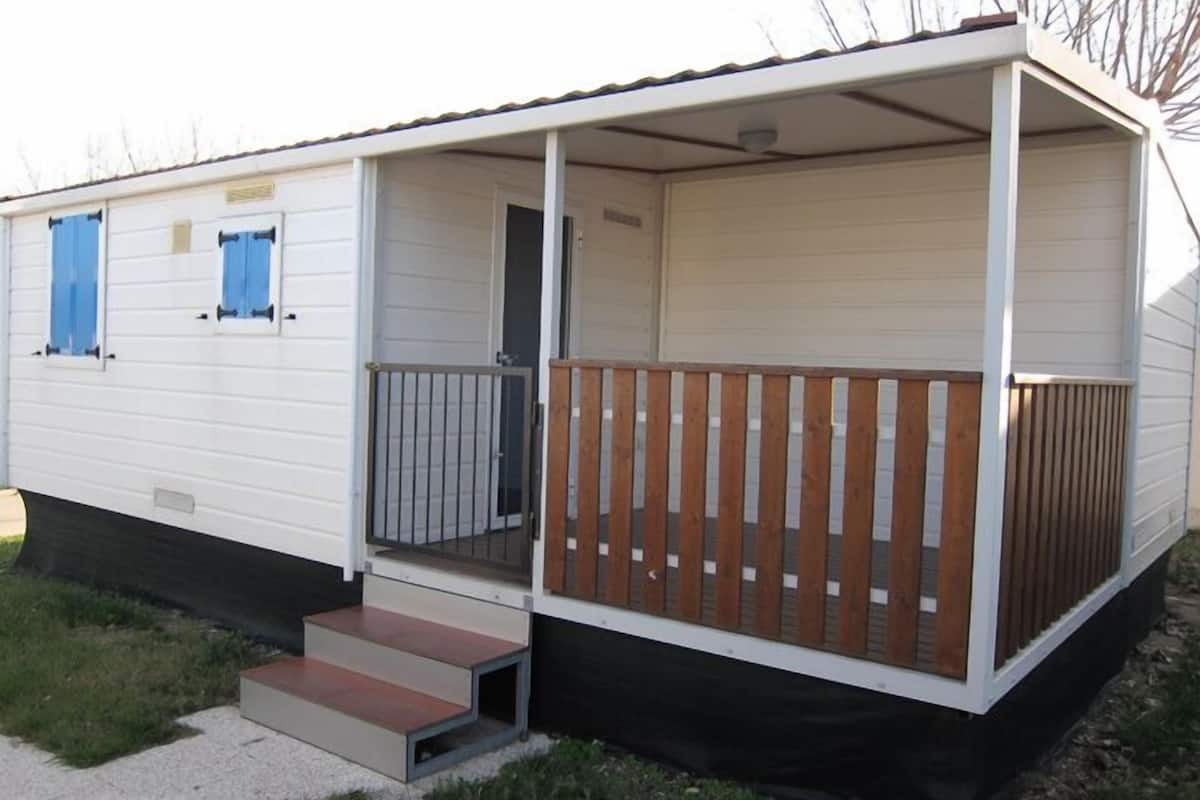 A mobile home with a porch, a small set of steps, and a fenced area.