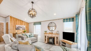 A cozy living room with a fireplace, a sofa set, and a television. - Aberdunant Hall (Porthmadog)