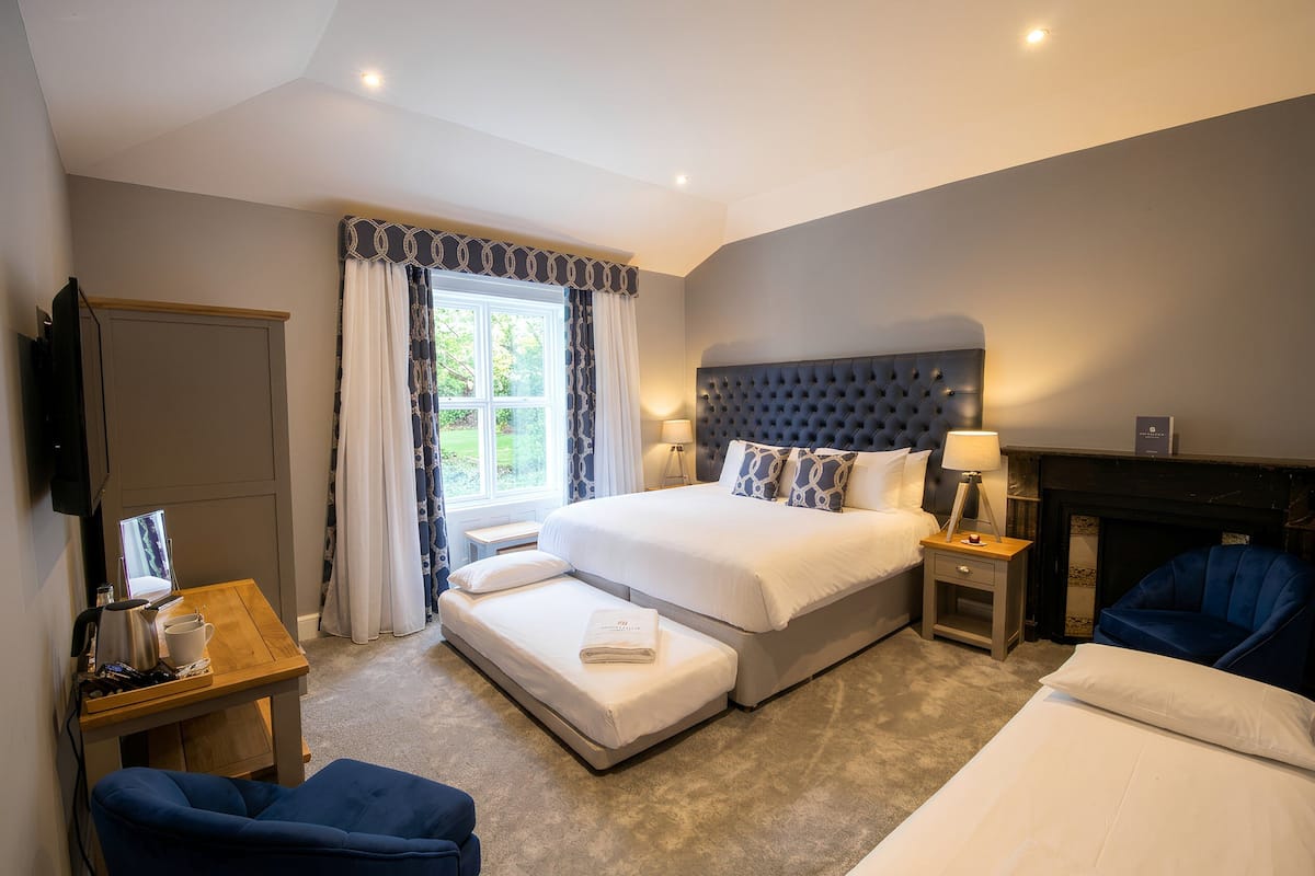 A bedroom with a large bed, bedside tables, a TV, and a fireplace.