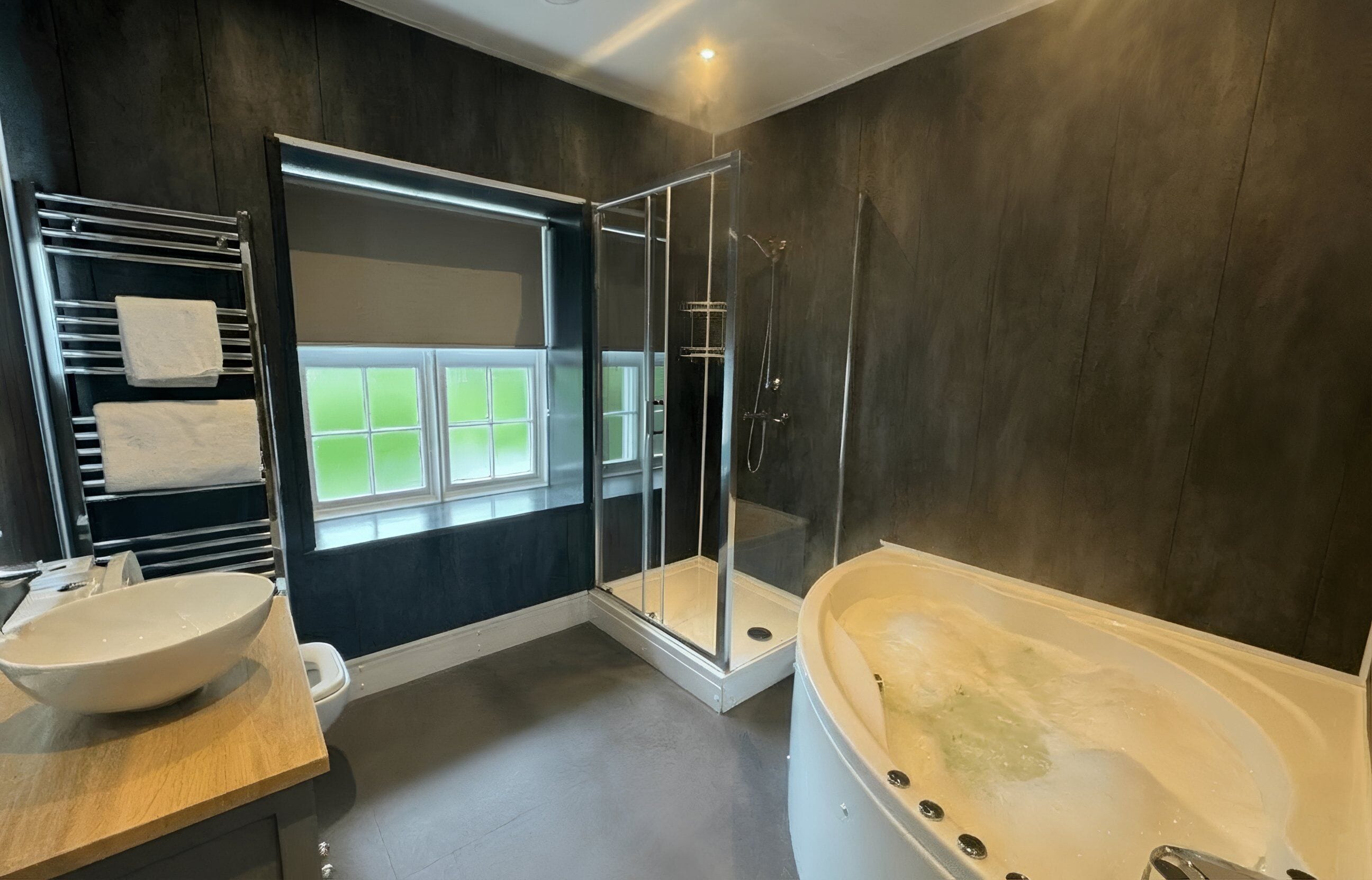A modern bathroom with a bathtub, shower, and a window.