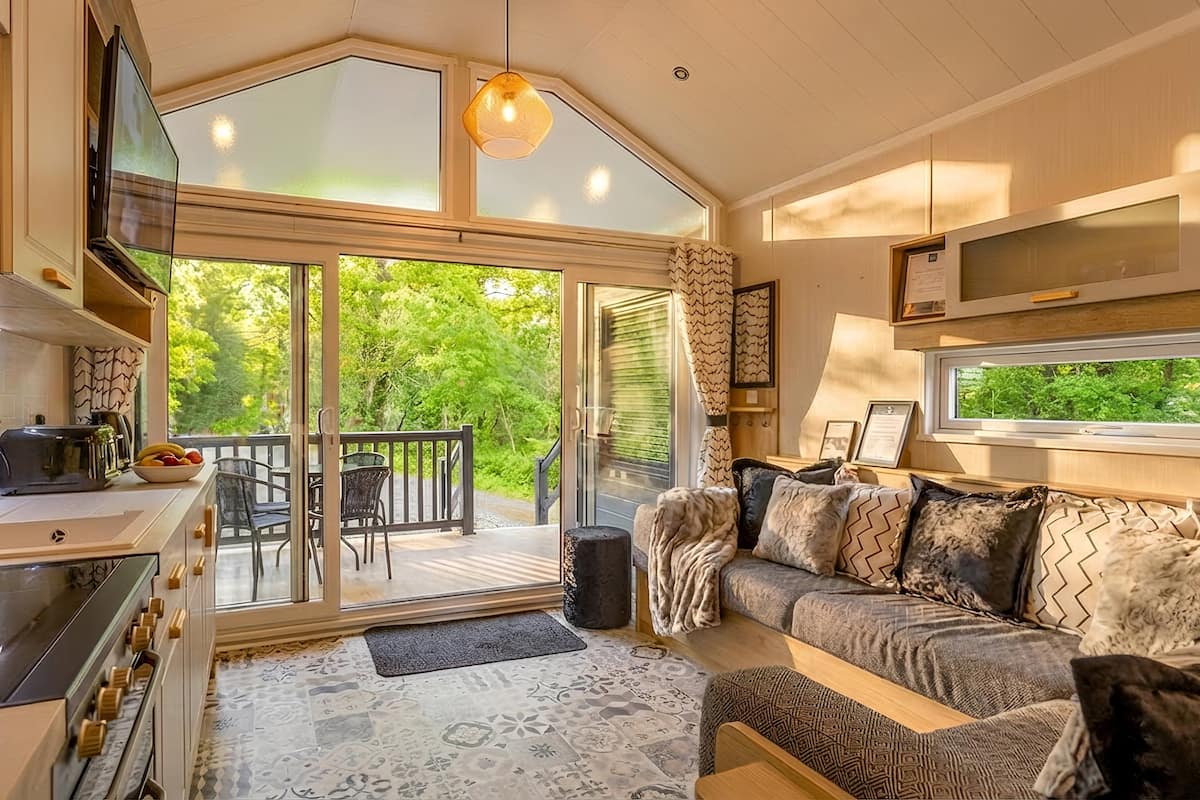 A cozy cabin interior with a kitchen, dining area, and a sofa with patterned cushions.