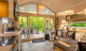 A cozy cabin interior with a kitchen, dining area, and a sofa with patterned cushions. - Aberdunant Hall (Porthmadog)
