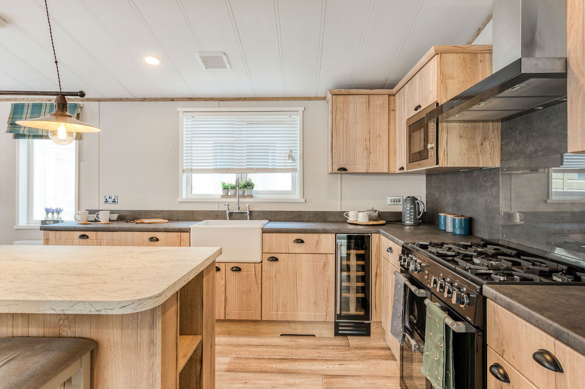 A modern kitchen with wooden cabinets, a built-in dishwasher, a stove, and a window with blinds.