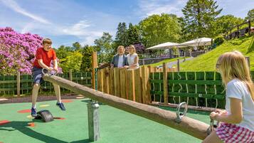 Children can play on the seesaw and explore the playground surrounded by trees and flowers.