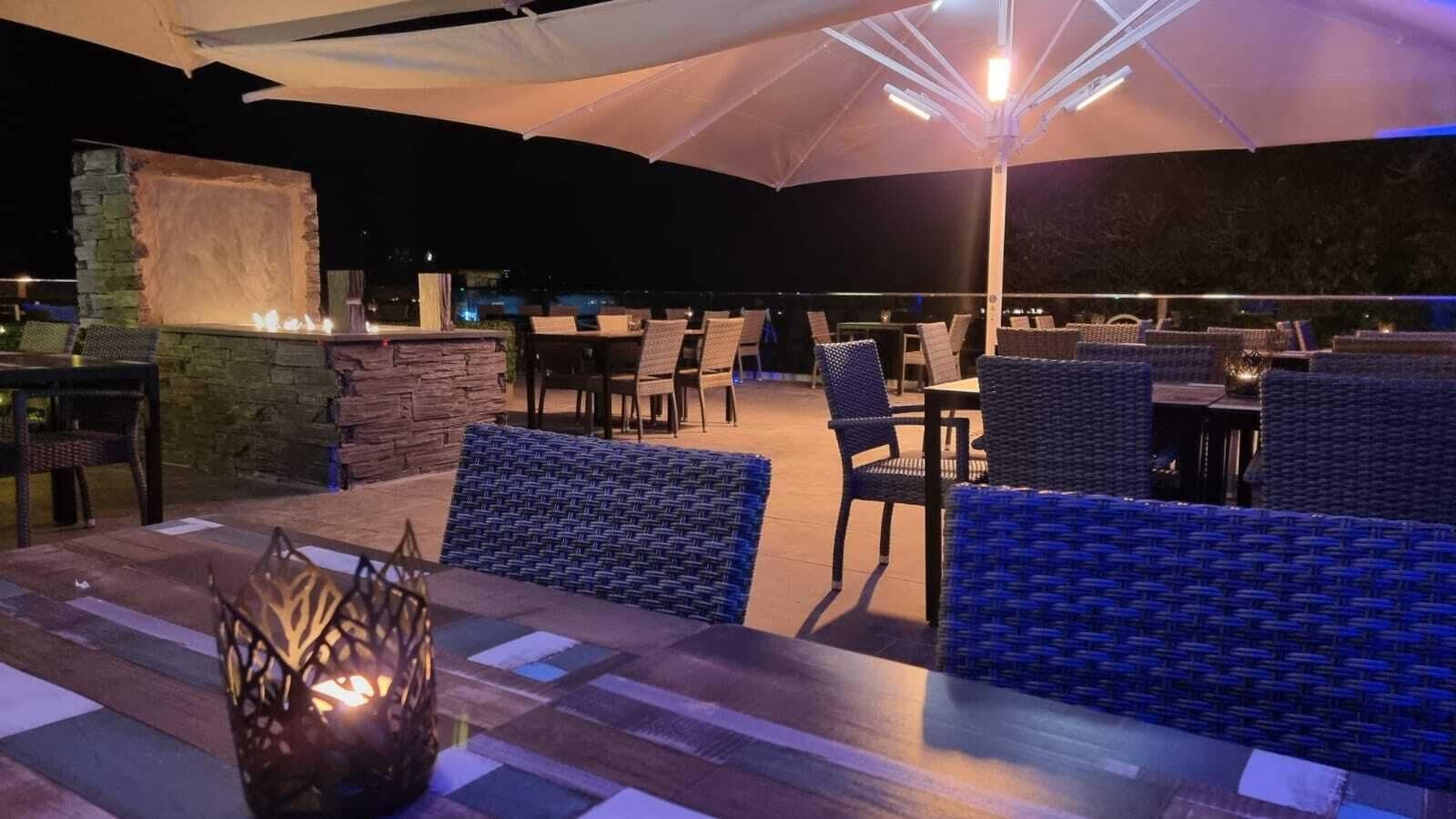 An outdoor seating area with wicker furniture, stone walls, and a fire feature.