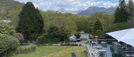 Une vue d’un espace aménagé avec une pelouse, des arbres et un bâtiment doté d’une terrasse.