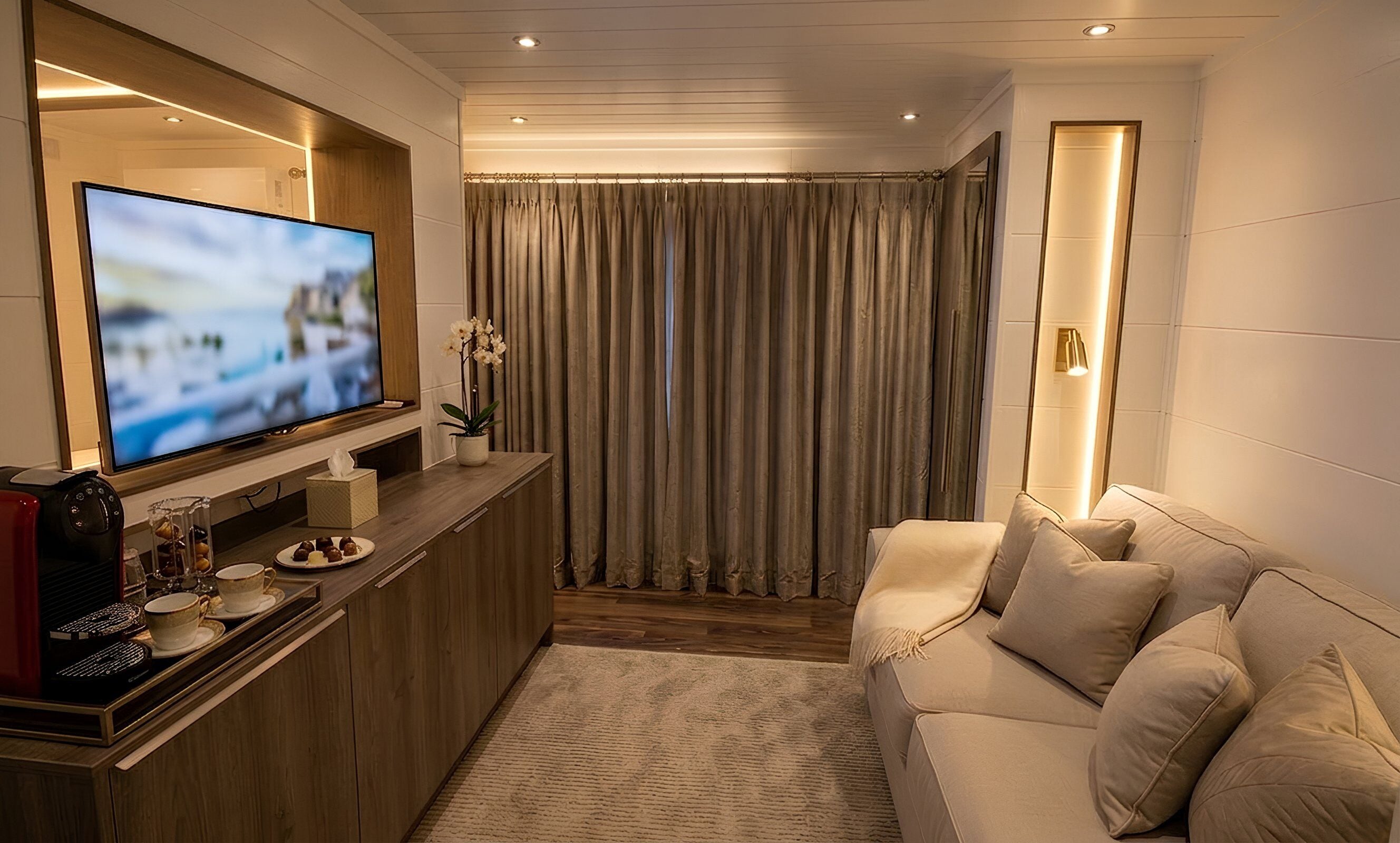 Een moderne woonkamer met een flatscreen televisie, een houten tv-meubel en een beige bank.