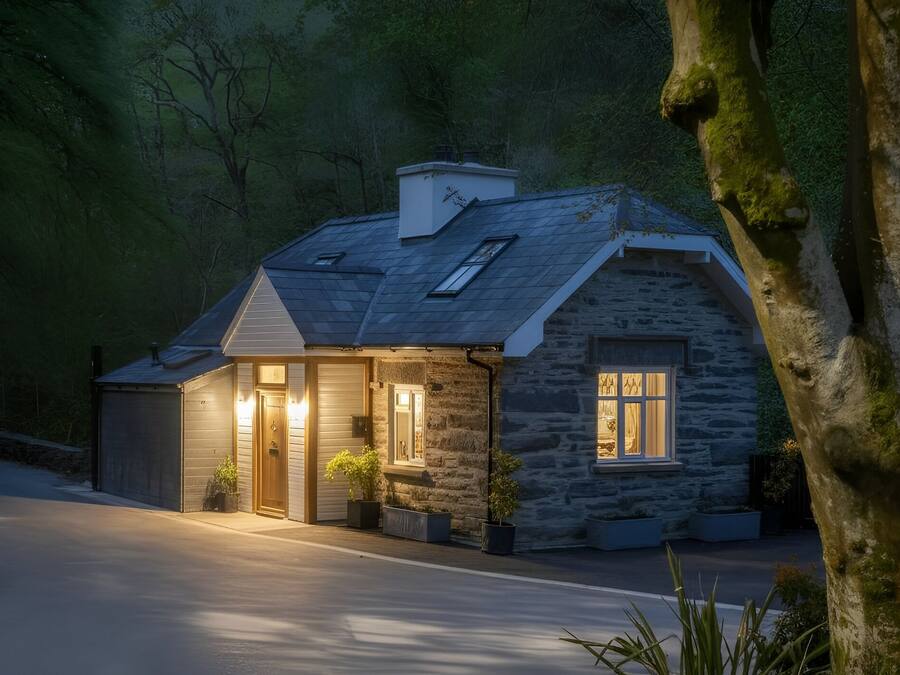 A stone house with a sloped roof, a garage, and a driveway.