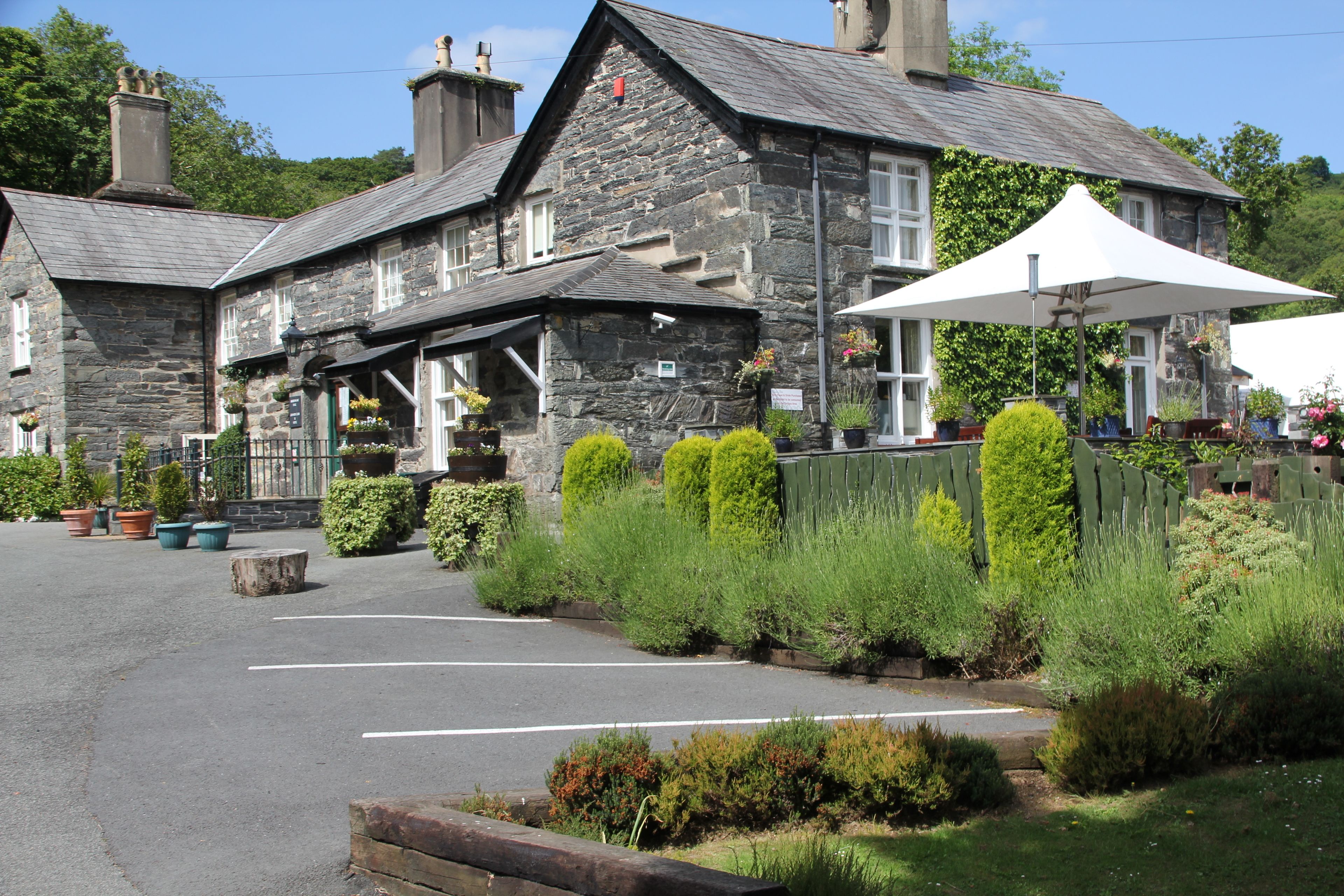 A stone building with a large umbrella and potted plants.