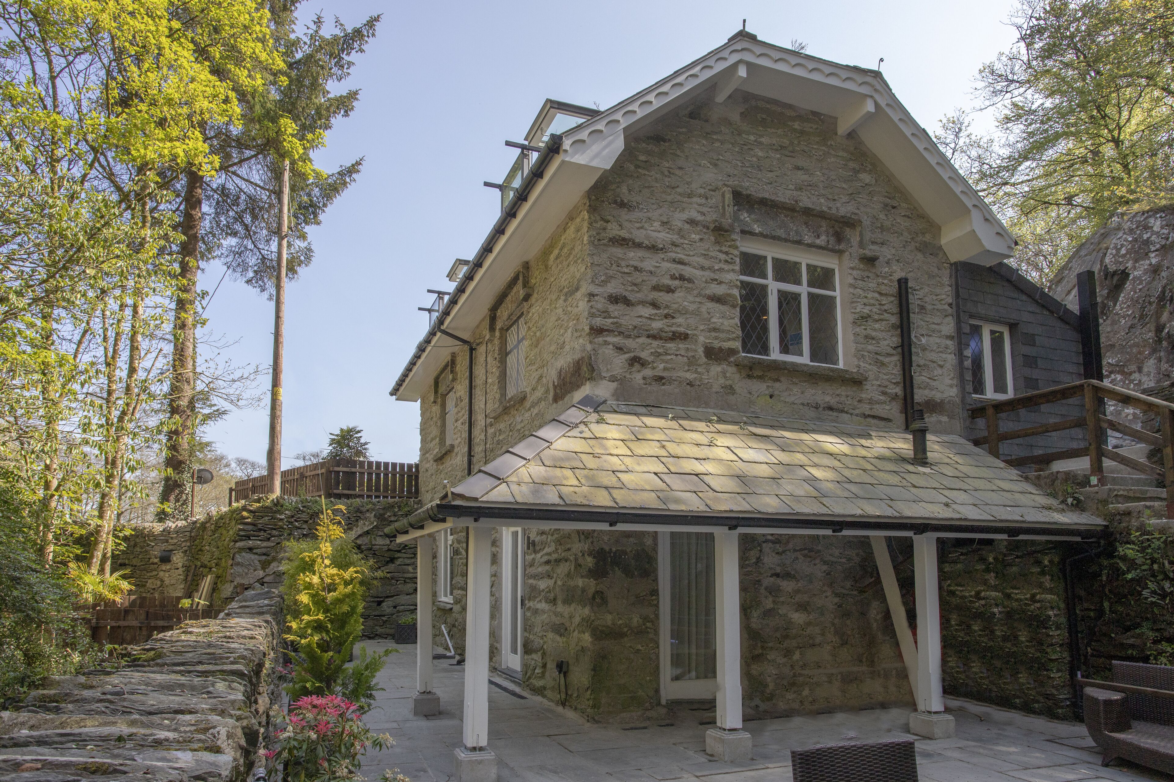 A stone building with a covered patio and a staircase leading to a wooden deck.