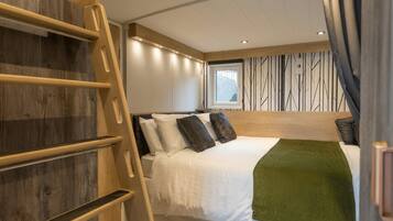 Un dormitorio con una cama, un edredón verde, una escalera de madera y una ventana con vistas.