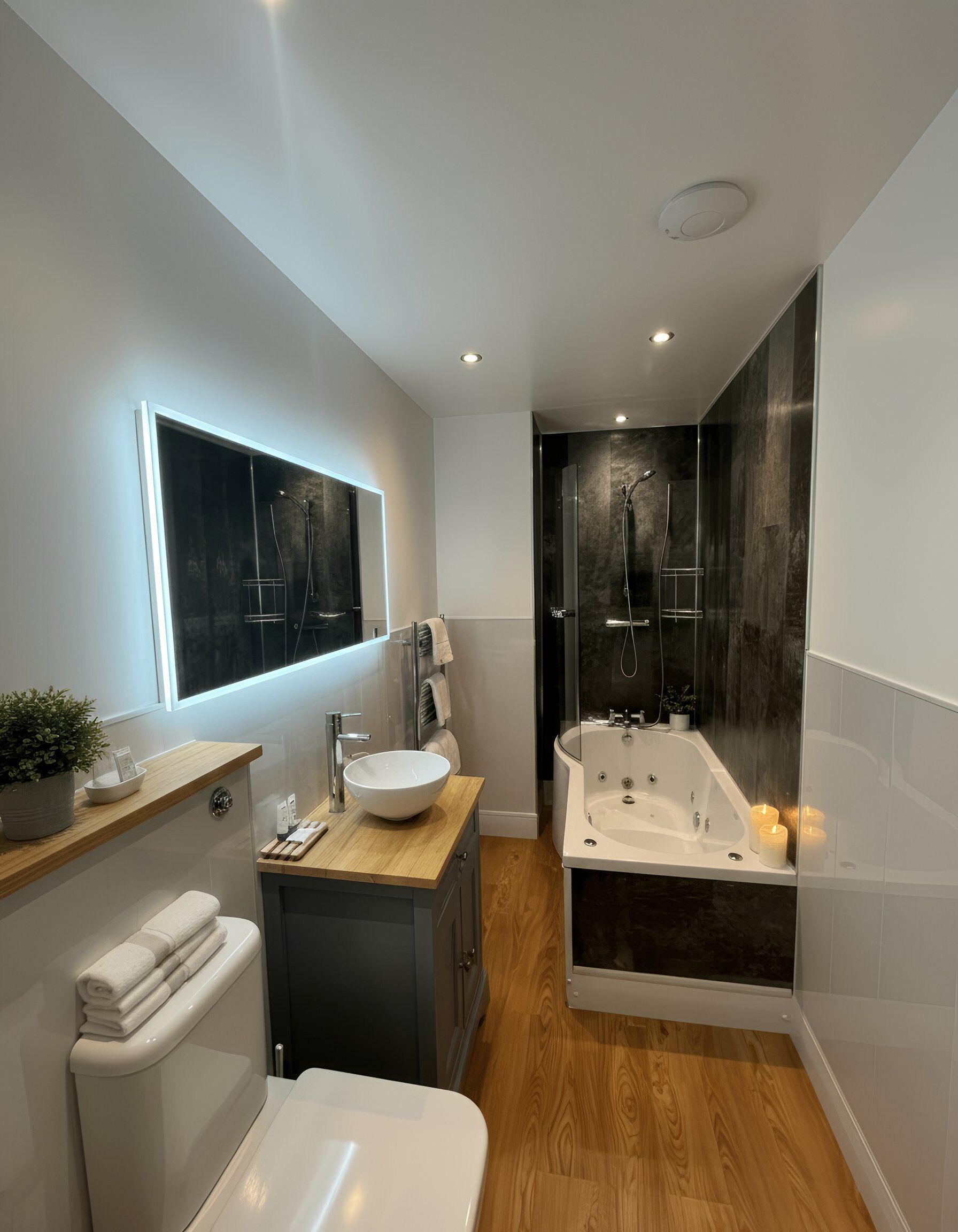 Un baño moderno con un espejo grande, un lavamanos, un inodoro y una bañera.