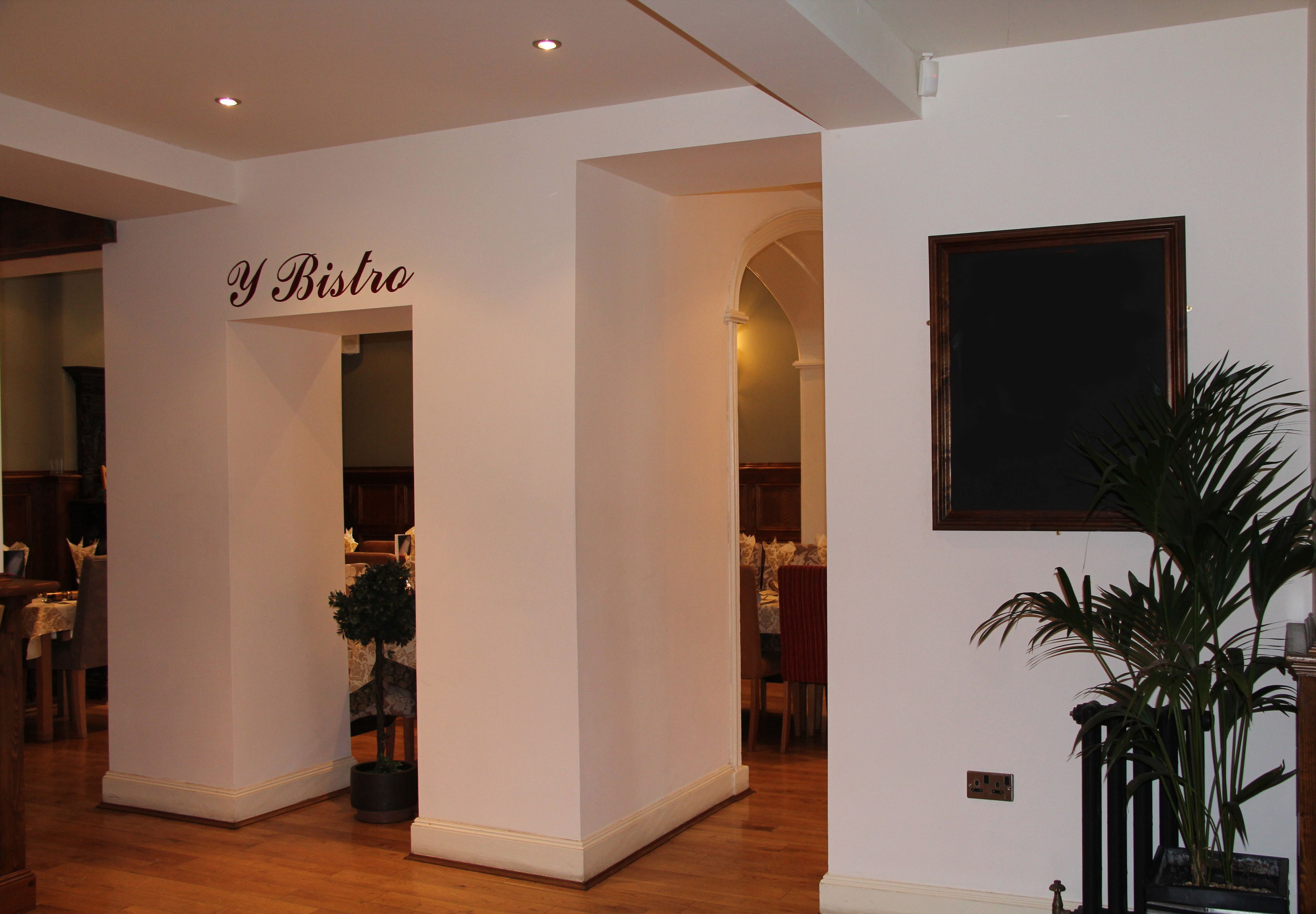 Un couloir avec une enseigne indiquant « Y Bistro » et une plante en pot.