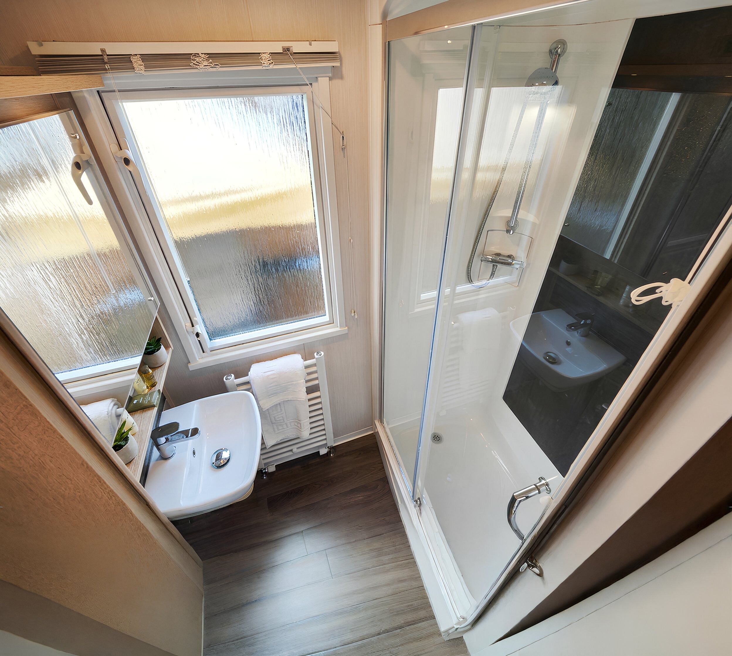 Un baño con cabina de ducha de vidrio, lavabo y ventana.
