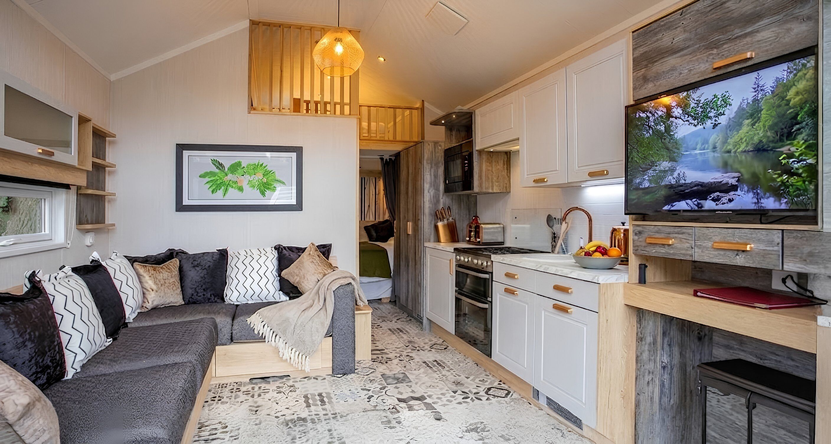 A modern living room with a sofa, a television, and a kitchen area with cabinets and a stove.
