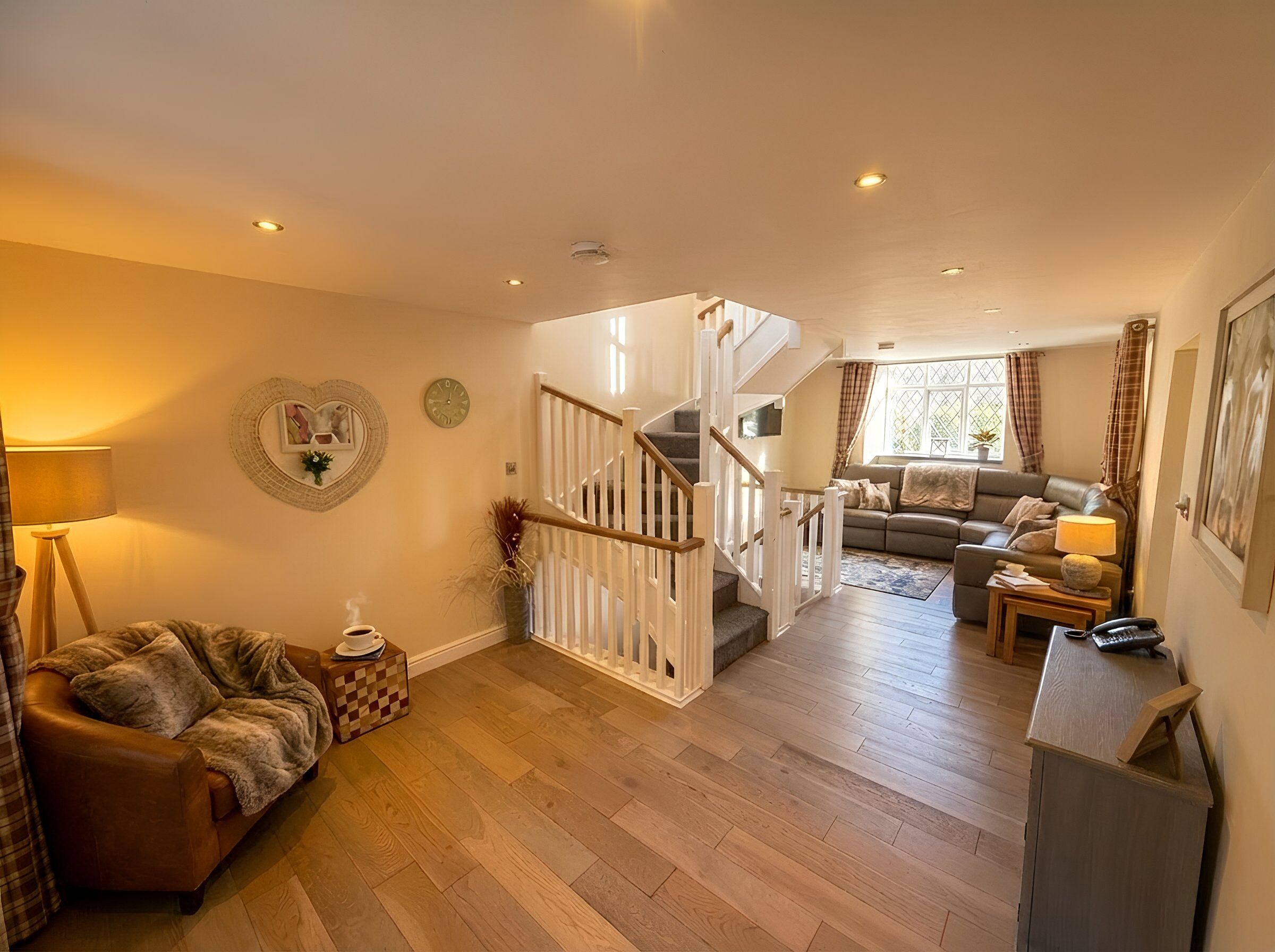 A spacious living area with a staircase, a sofa, a coffee table, and a lamp.