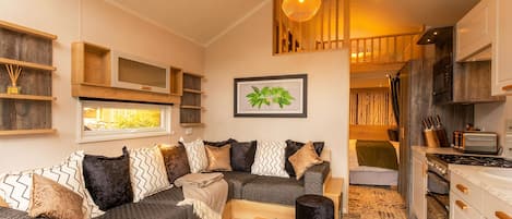 A cozy living area with a sofa, a coffee table, and a kitchen with a stove and cabinets.