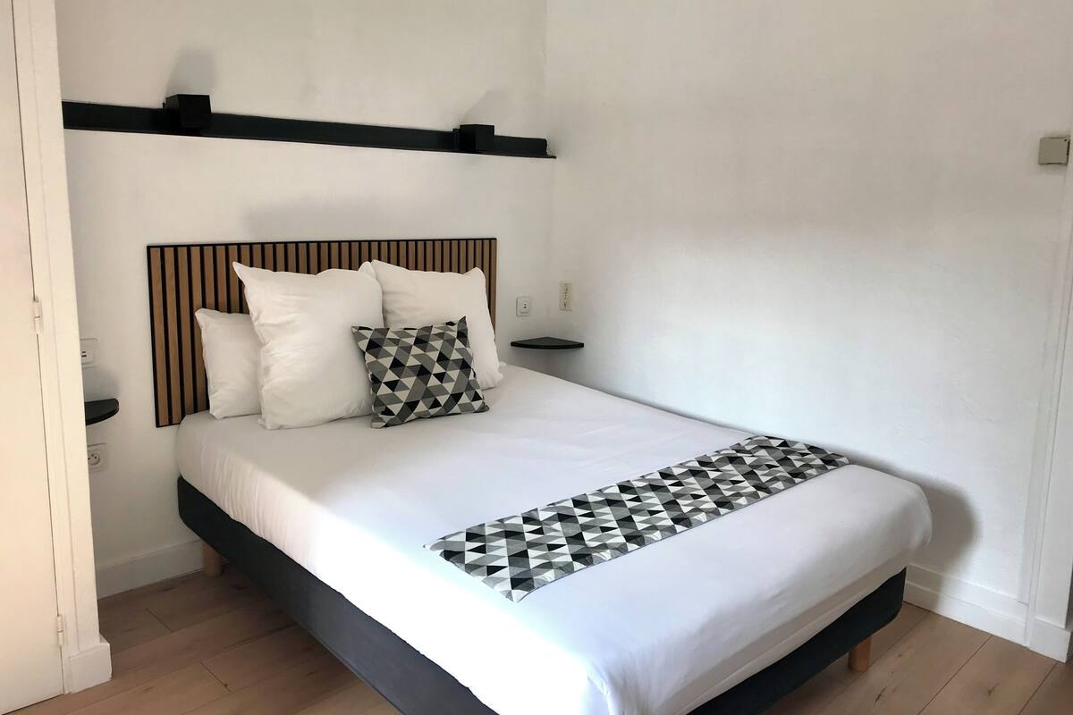 A modern hotel room with a bed, a headboard, and a bedside table.