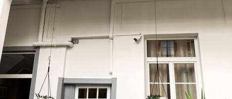 A multi-story building with balconies, potted plants, and a security camera.
