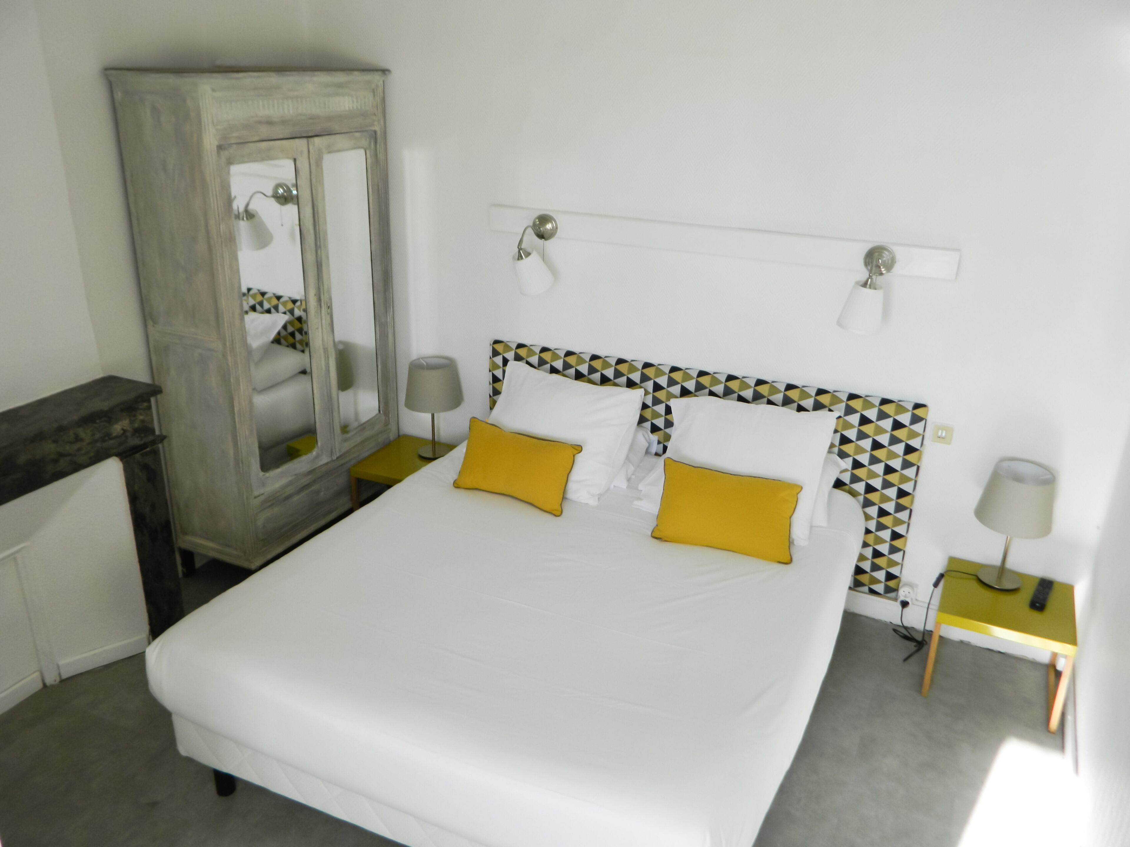Quarto bem arrumado com cama, mesas de cabeceira, guarda-roupa e espelho.