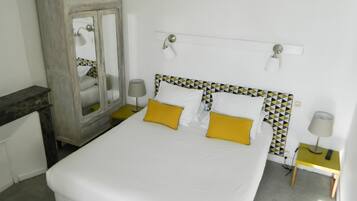 Quarto bem arrumado com cama, mesas de cabeceira, guarda-roupa e espelho.