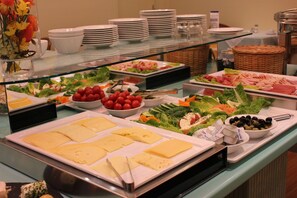 A buffet with various food items including cheese, salads, and meats. - Hotel Cabo (Hamburg)
