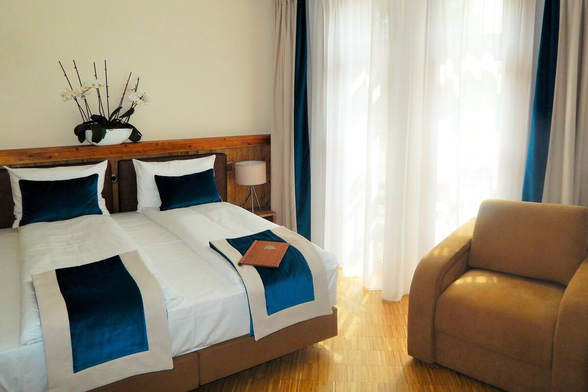 Una habitación de hotel con cama, una silla, una mesita de noche y una lámpara.