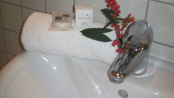 A bathroom sink with a white towel and Starline soap on a shelf.