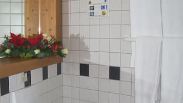 A bathroom with a toilet, sink, and a mirror above the sink. There is a sign on the wall and a towel rack with towels.