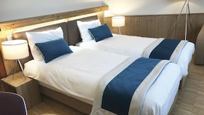 Una cama doble con ropa de cama blanca y azul, dos lámparas de noche y un cabecero de madera.