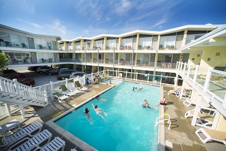 A pool area with multiple levels of balconies, lounge chairs, and a clear blue sky.