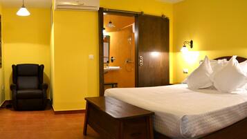 Een hotelkamer met een bed, een stoel, een nachtkastje en een kledingkast.