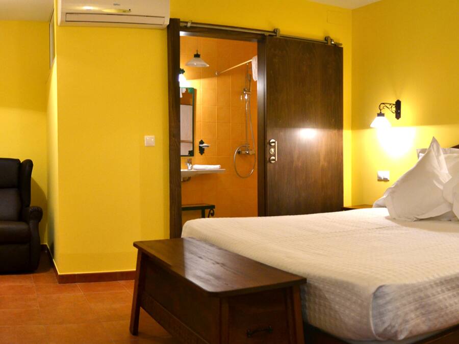 Een hotelkamer met een bed, een stoel, een nachtkastje en een kledingkast.