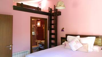 A bedroom with a bed, a wooden ladder, a bathroom visible through an open door, and a pink wall.