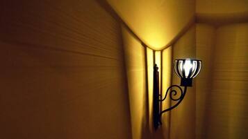 Un couloir avec un luminaire fixé au mur et un rideau.